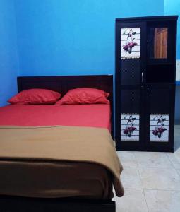 1 cama con almohadas rojas y pared azul en Penginapan Herlandy, en Komodo Labuan Bajo Airport