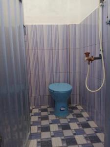 Un baño con inodoro azul y ducha. en Penginapan Herlandy, en Komodo Labuan Bajo Airport