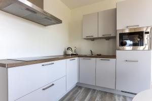 Una cocina blanca con gabinetes blancos y un microondas. en Uithaven 10B Kamperland, with harbour views, en Kamperland 25 fotos más