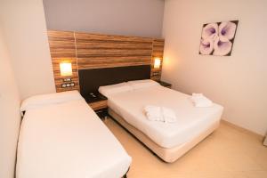 two beds in a small room with white sheets at Magic Inn in Oropesa del Mar +3 photos