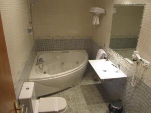 y baño con bañera, aseo y lavamanos. en Hotel Galayos, en Hoyos del Espino