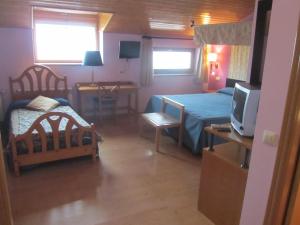 1 dormitorio con 1 cama y 1 mesa con TV en Hotel Galayos en Hoyos del Espino