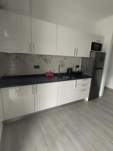 a kitchen with white cabinets and black counter tops at Vila Ramos I in Funchal