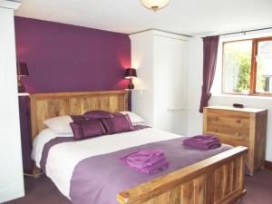 a bedroom with a bed with purple pillows on it at Old Sheepcote in Broadway