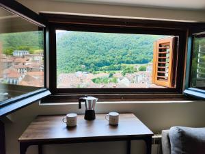 a window with a table with two mugs on it at Apartamento ático Belabarce in Isaba