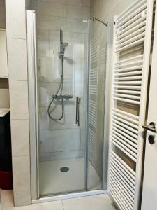 a shower with a glass door in a bathroom at Cozy Cloche Nest - Studio in Luxembourg