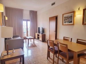 Una sala de estar con una mesa, un sofá y un televisor. en Hotel Monarque Costa Narejos, en Los Alcázares