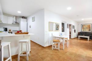 une cuisine et un salon avec des comptoirs et des tabourets blancs dans l'établissement Minipiso Tejina de Isora, à Guía de Isora