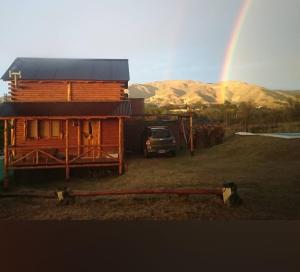 a wooden cabin with a rainbow in the background at Cabaña jacaranda in Valle Hermoso +4 photos