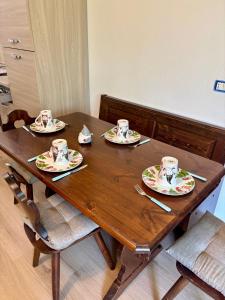 a wooden table with four plates and cups on it at Chalet dello gnomo in Folgarida