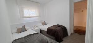 ein weißes Zimmer mit zwei Betten und einem Fenster in der Unterkunft Collado, terraza con vistas y garaje - Arafita Apartamentos in Formigal