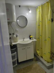 a bathroom with a sink and a yellow shower curtain at Casa Rajac - By Isak in Polom