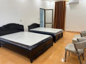 2 camas en una habitación con silla y espejo en Khách Sạn Gia Hưng, en Ninh Binh