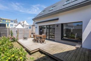 a deck with a table and chairs on a house at Le 50 Bis - Proche plage in Locmiquélic