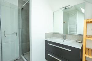 a bathroom with a sink and a shower with a mirror at Le 50 Bis - Proche plage in Locmiquélic +6 photos