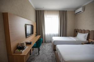 a hotel room with two beds and a television at Kaganat Boutique Hotel in Osh