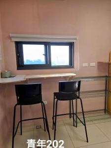 deux chaises dans une pièce avec un comptoir et une fenêtre dans l'établissement Kunba Homestay, à Hualien