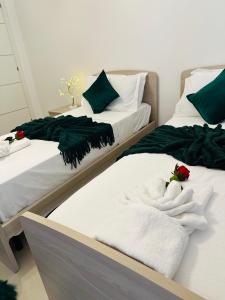 two beds with green and white towels on them at Couple's Getaway in Is-Swieqi