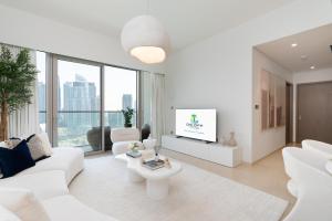 a white living room with a white couch and a tv at Grande, Luxurious 2 BR, Burj Khalifa & Fountain view in Dubai