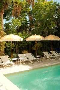 a group of chairs and umbrellas next to a pool at Hôtel Le Sud in Juan-les-Pins