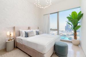 a white bedroom with a large bed and a large window at Grande, Luxurious 2 BR, Burj Khalifa & Fountain view in Dubai +39 photos