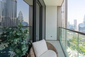 a balcony with a chair and a potted plant at Grande, Luxurious 2 BR, Burj Khalifa & Fountain view in Dubai
