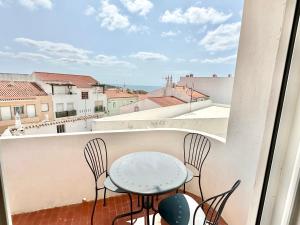a table and chairs on a balcony with a view at Apartamento com vista mar no centro antigo in Bicas