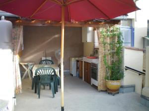 a kitchen with a table and an umbrella at T2 dans maison de village in Ganges