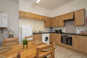a kitchen with wooden cabinets and a table and a refrigerator at Albert Lodge in Belfast