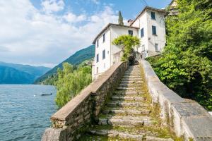 a building on a hill next to a body of water at GuestHost - Lovely studio with balcony a few mt from the lake in Nesso