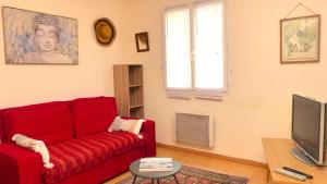 ein Wohnzimmer mit einem roten Sofa und einem Fernseher in der Unterkunft Maison proche de la rivière du Bono, entre Auray et Vannes in Plougoumelen