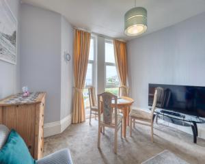 a living room with a table and chairs and a television at Apartment 2 - 1 Bedroom Sea Front-Sea Views-Free Parking in Paignton