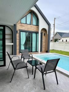 a patio with chairs and a table next to a swimming pool at N&C Mountain Pool Villa Huahin in Hua Hin