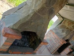 an outdoor brick oven with a stone wall at Casa Anna in Tăşnad