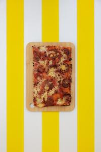 a slice of pizza sitting on a cutting board at Hôtel Le Sud in Juan-les-Pins