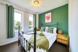 Un dormitorio con una cama y una pared verde. en 2BR City Flat Walk to Buchanan Hydro with Parking, en Glasgow