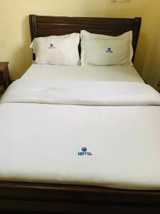 a bed with white sheets and pillows in a room at DF HÔTEL Plazza in Yaoundé