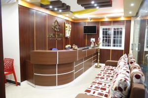 a lobby with a bar with a couch and a tv at Hotel New Amirtham inn in Palani
