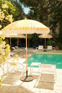 an umbrella and chairs next to a swimming pool at Hôtel Le Sud in Juan-les-Pins