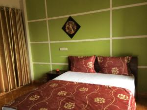a bedroom with a bed with red pillows and green walls at Hai Duong Hotel in Hòa Bình