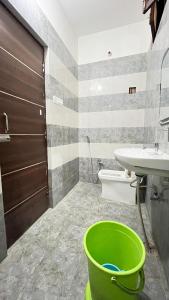 a bathroom with a green bucket in front of a sink at Hotel kashi vaas in Kakarmatha