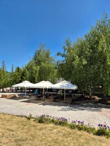 eine Terrasse mit Tischen und weißen Sonnenschirmen in der Unterkunft Hotel Junior in Kopaonik