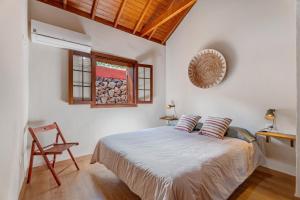 a bedroom with a bed and a chair and a window at Complejo Rural Pajar de Bento in Agulo