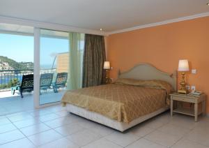 a bedroom with a bed and a balcony at Paleokastritsa Palace - Adults Only in Paleokastritsa +49 photos
