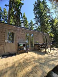a cabin with a wooden deck with a picnic table at Stuga med strandbastu in Oravais
