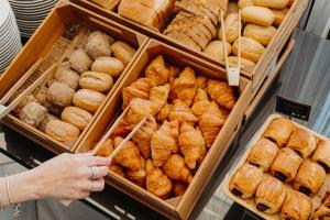 a person reaching for a tray of pastries in a bakery at Velamar Boutique Hotel - Adults Friendly in Albufeira