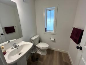 a white bathroom with a toilet and a sink at Seton Villas Cozy Four-bed house in Calgary +23 photos