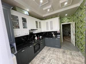 une cuisine avec des armoires blanches et des comptoirs noirs dans l'établissement Home comfort near Samarkand airport, à Samarcande 12 autres photos