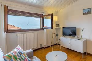 a living room with a couch and a tv and a window at ROMANTIC COMO HIDEAWAY with private parking and AirCon in Acquaseria