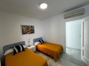 twee bedden in een kamer met oranje lakens bij CONIL CENTRO MERCURIO solo FAMILIAS in Conil de la Frontera